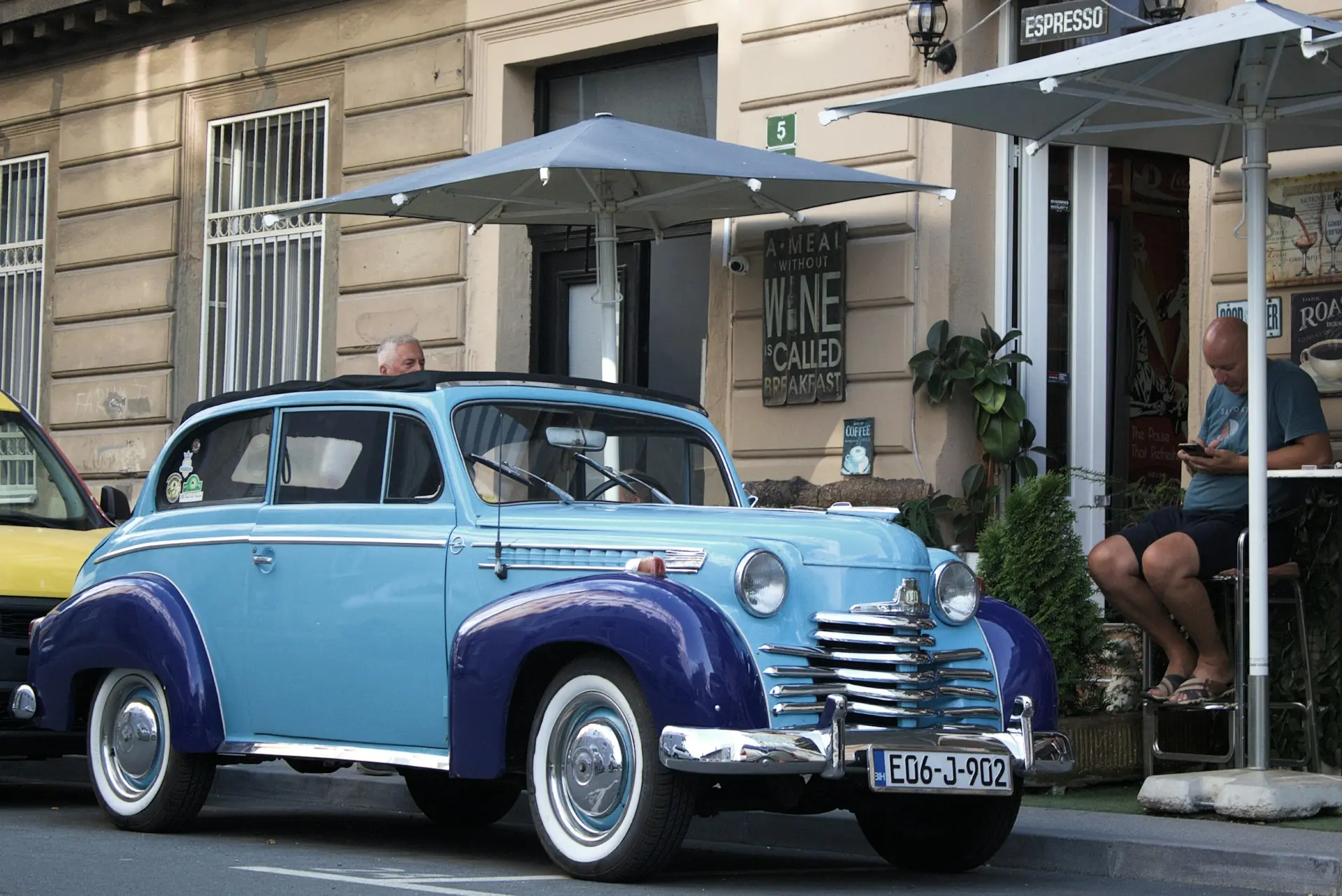 A blue and yellow car driving down a street